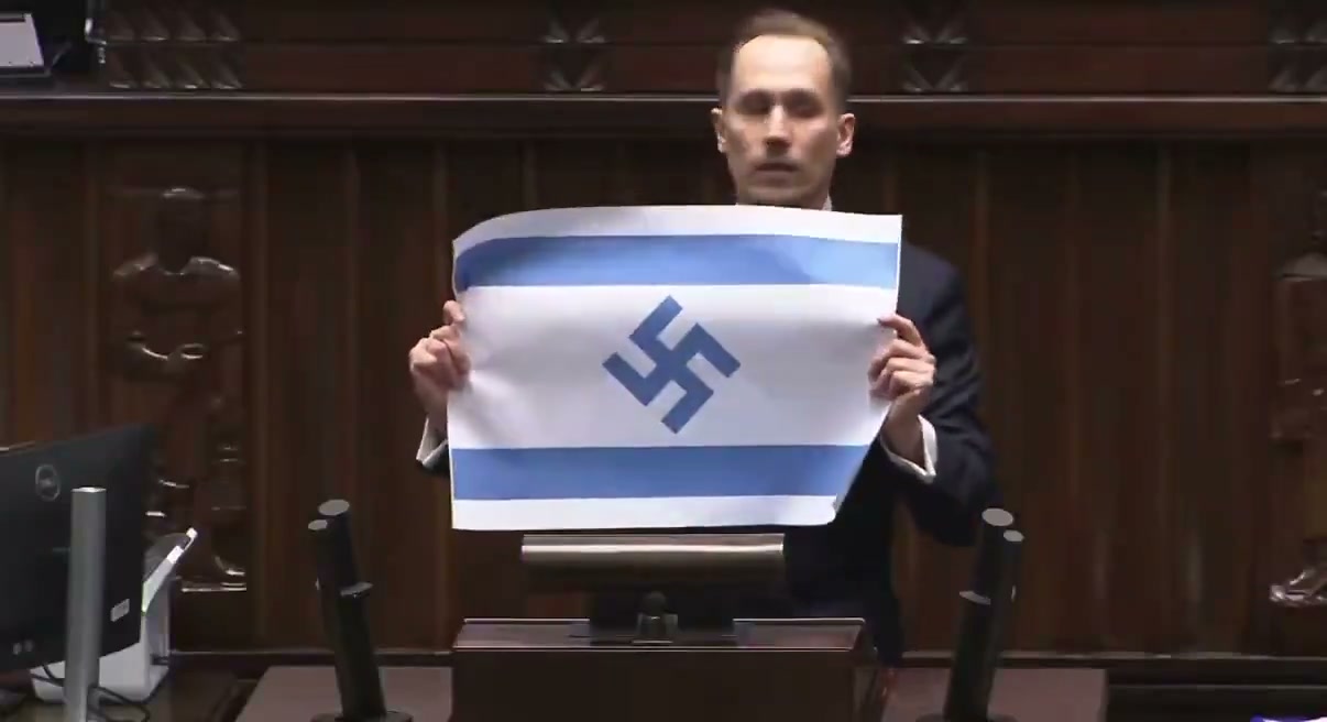 The Israeli flag with a swastika Berkowicz displayed at the rostrum (April 14, 2026)