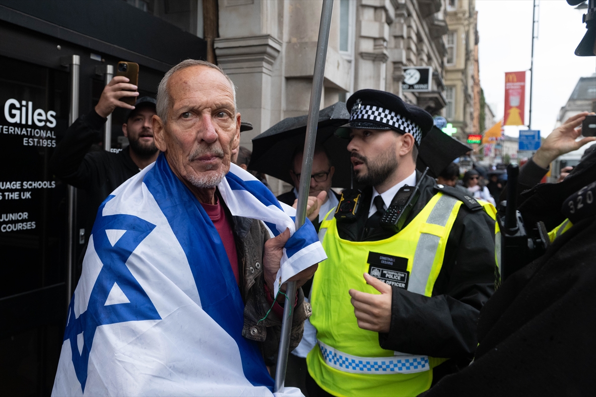 A person carrying an Israeli flag and police during the march in London