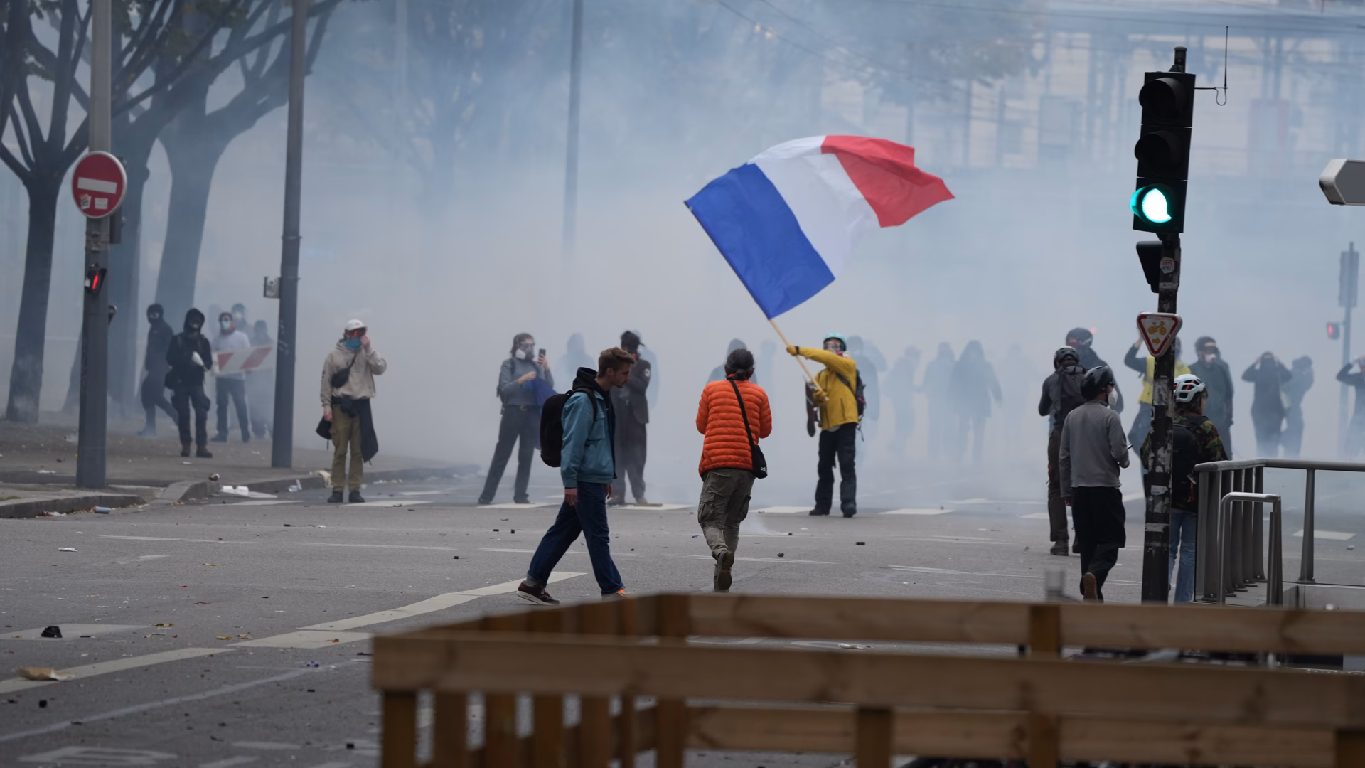 A protester waves a French flag amid tear gas (AA)