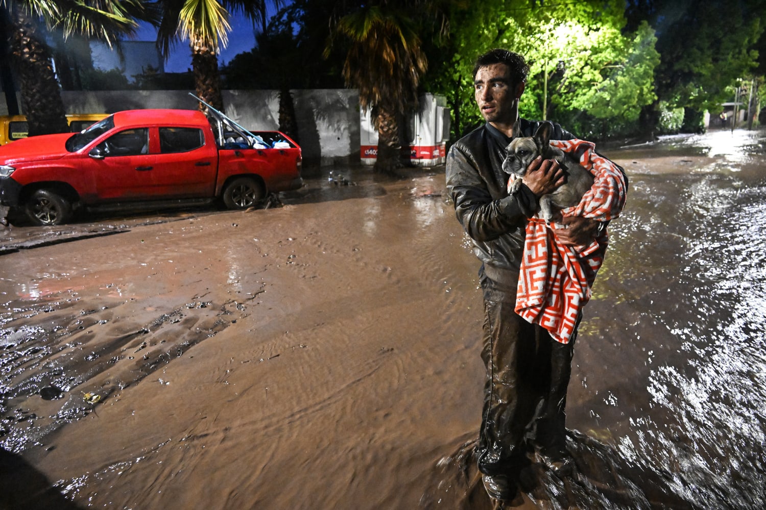 A man carries his dog through a mud-filled street in Las Condes, Santiago