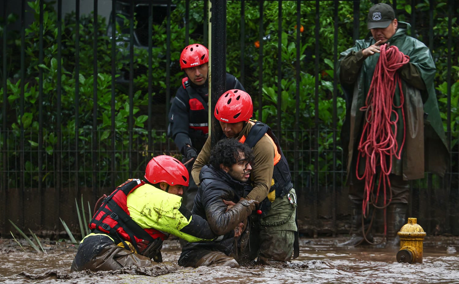 Rescuers pull a resident from floodwater in San Carlos de Apoquindo