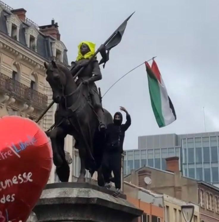 متظاهر ملثم يرفع العلم الفلسطيني فوق تمثال لفارس